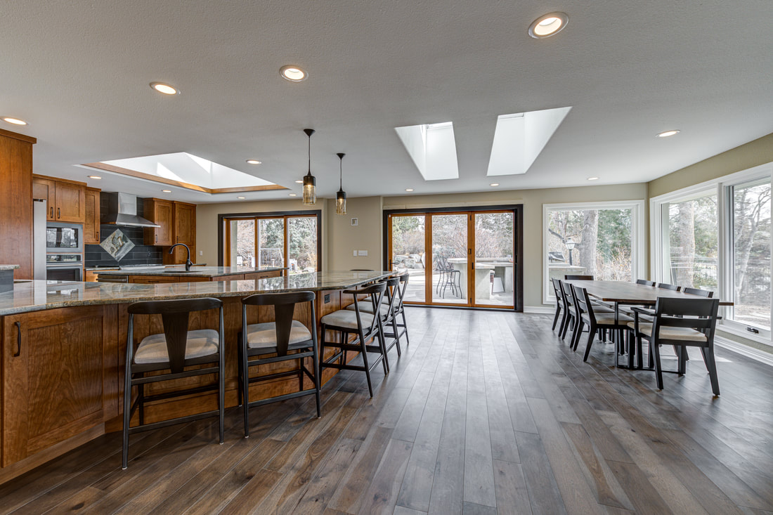 Open kitchen with custom cabinetry, island seating, and large windows